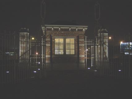 Photo de nuit d'une maison de portier (de la gare de formation des Deux-Îles?) transportée sur un rond point d'Anderlecht.