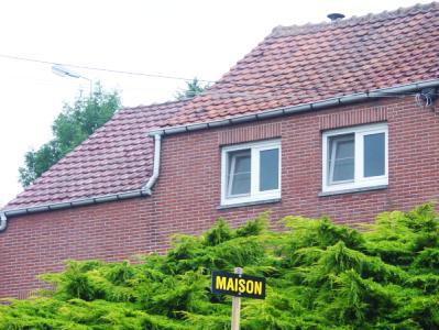 Photo d'une maison devant laquelle se trouve un panneau «Maison» la partie «à vendre» étant tombée)